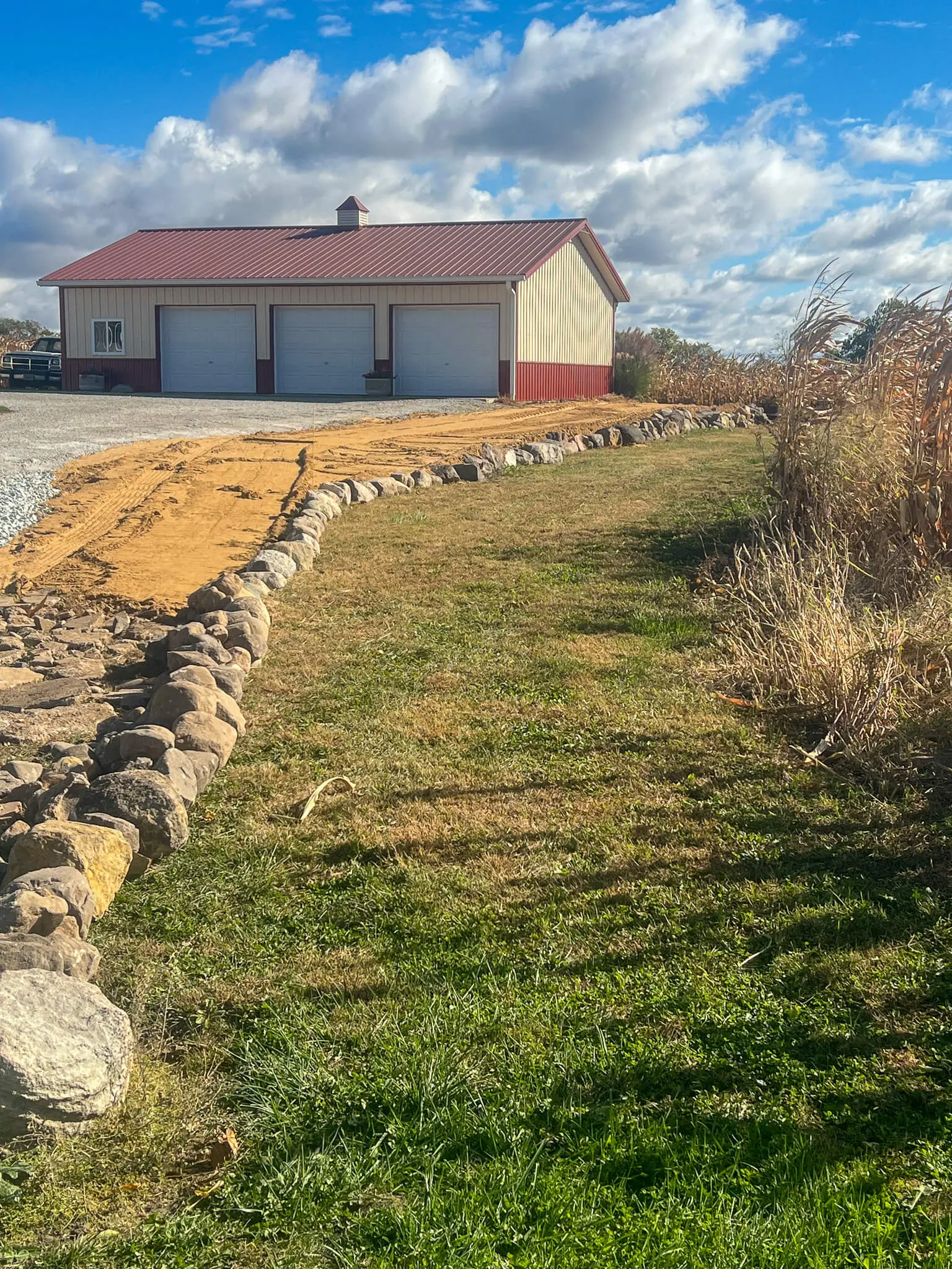 Drainage swale and gravel drive graded beside a pole barn
