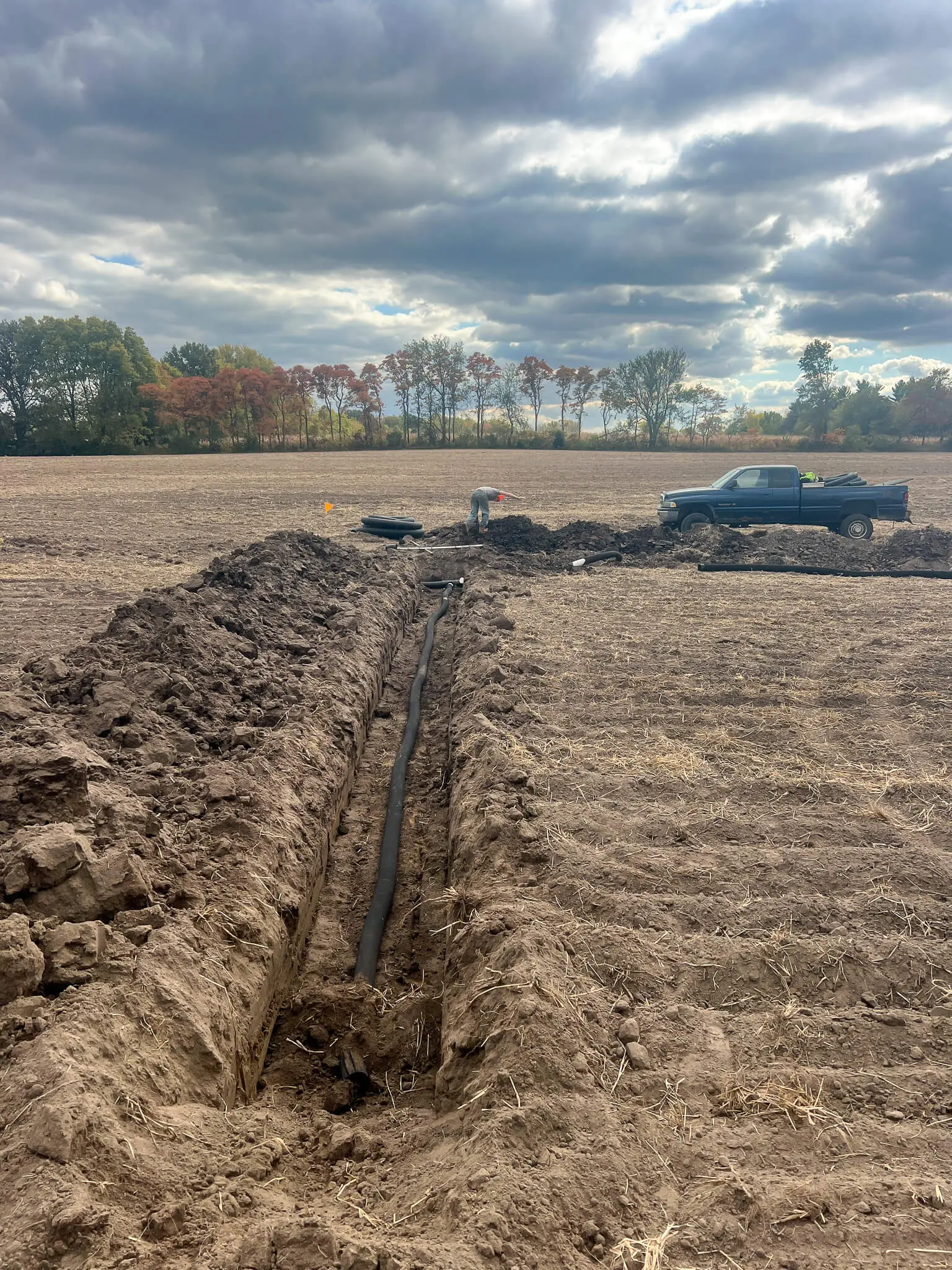 Farm tile trench with the crew running new drainage pipe